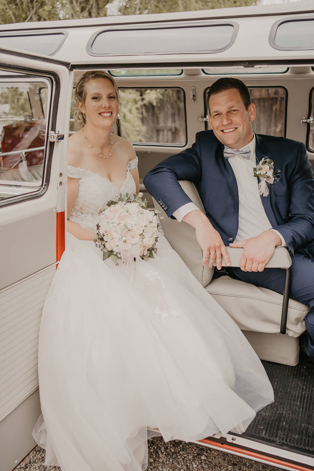 brautpaar sitzt im auto und laechelt