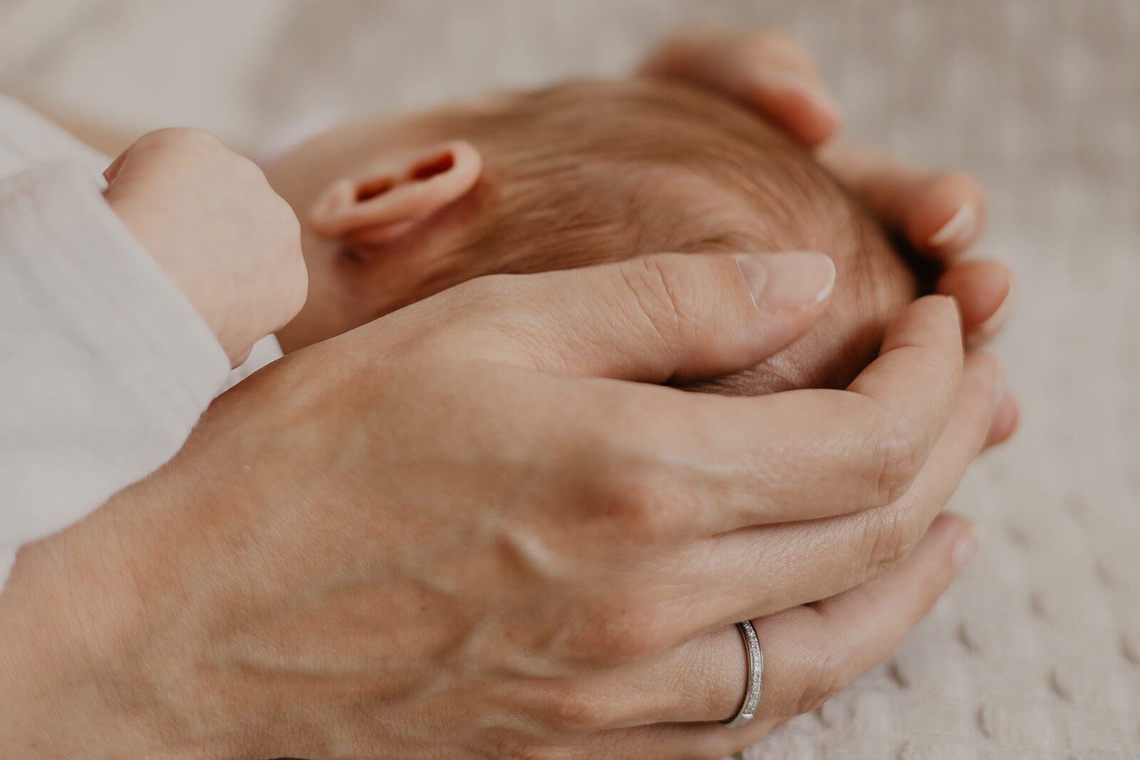 eine mutter haelt mit den haenden den kopf ihres neugeborenen kindes
