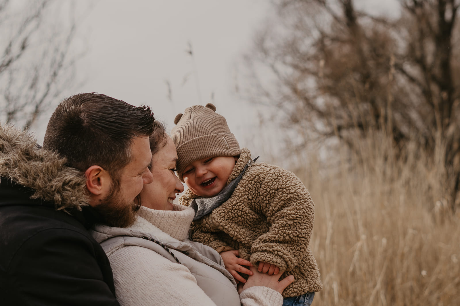 eine familie die innig kuschelt ein kind das auf dem arm der mutter lacht